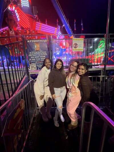 Team members at a night fair with the ride lights behind them
