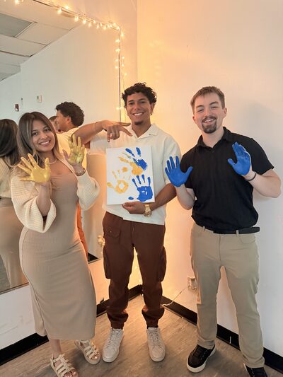 Team members holding up a canvas of painted handprints