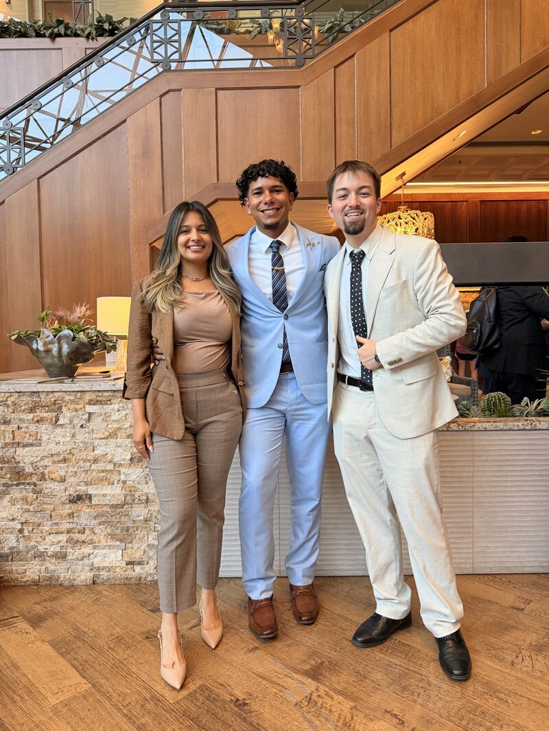 Three Relentless Marketing team members in business attire standing together at a company event